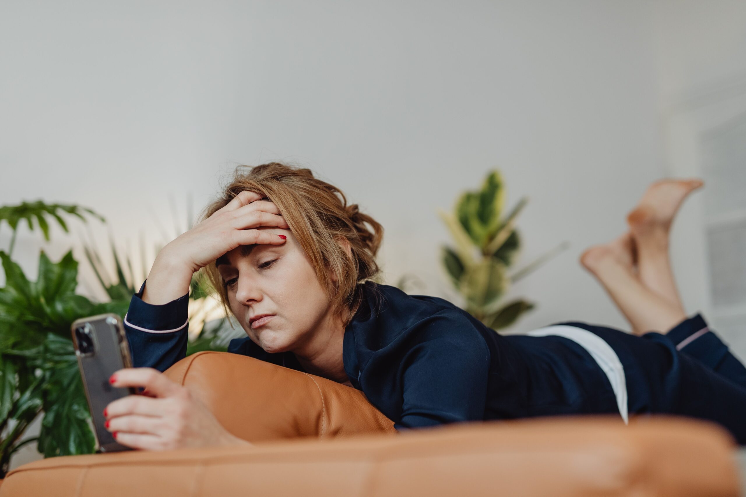 Frau blickt erschöpft auf ihr Smartphone – Symbolbild für digitalen Stress